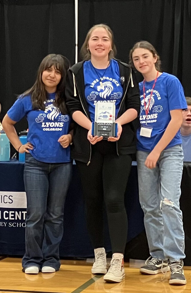 Three middle school girls posing for the camera holding their robotics award.